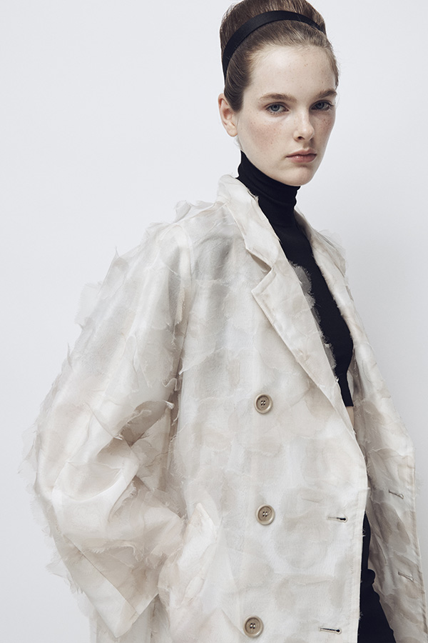Défilé Max Mara Printemps Été 2026 : mannequin avec look trench-coat blanc et col roulé noir.