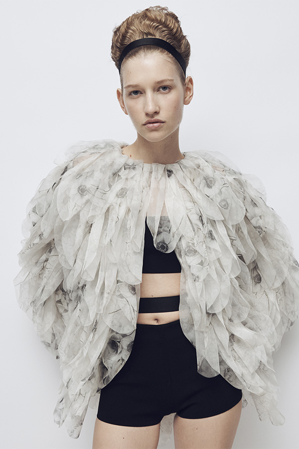 Défilé Max Mara Printemps Été 2026 : mannequin avec look veste blanche avec détails, haut à bride et short noirs.